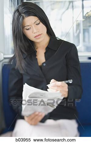 Stock Photography - Woman doing crossword in newspaper on bus or subway. Fotosearch