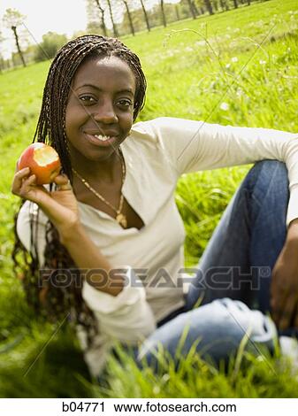 Woman eating apple in grass field View Large Photo Image Stock Image - Woman eating apple in grass field. Fotosearch