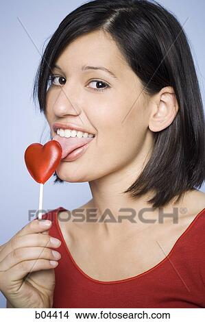 Woman eating heart-shaped lollipop View Large Photo Image Picture - Woman eating heart-shaped lollipop. Fotosearch