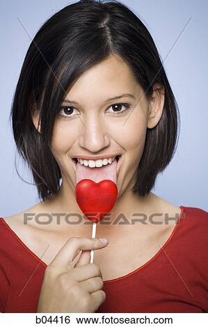 Woman eating heart-shaped lollipop View Large Photo Image Stock Photograph - Woman eating heart-shaped lollipop. Fotosearch