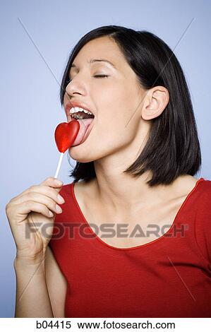 Woman eating heart-shaped lollipop View Large Photo Image Stock Photography - Woman eating heart-shaped lollipop. Fotosearch