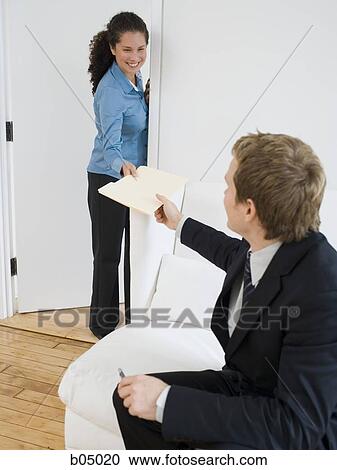 Stock Image - Woman giving businessman file folder. Fotosearch