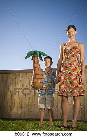 Woman holding hands with boy holding inflatable palm tree View Large Photo Image Stock Image - Woman holding hands with boy holding inflatable palm tree. Fotosearch