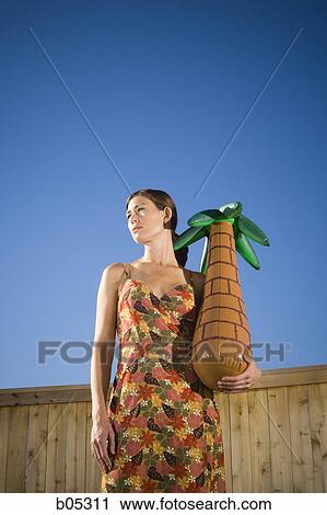 Stock Image - Woman holding inflatable palm tree. Fotosearch