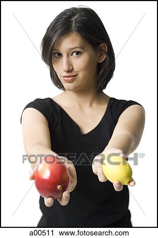 Stock Image - Woman holding out mango and lemon. Fotosearch