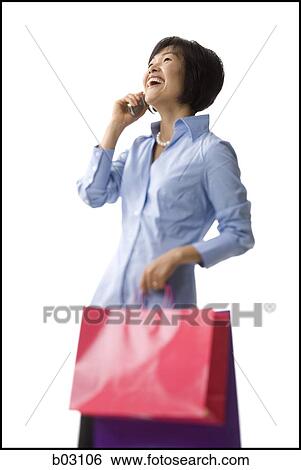 Woman holding shopping bags and talking on cell phone View Large Photo Image Stock Photograph - Woman holding shopping bags and talking on cell phone. Fotosearch
