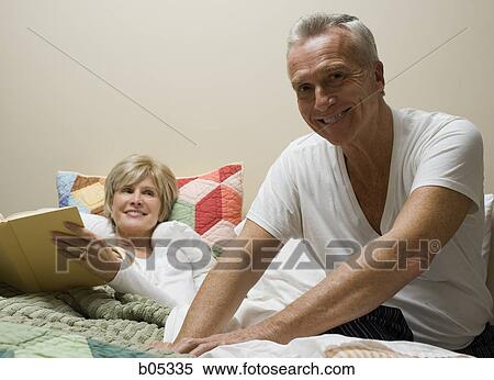 Woman in bed reading with mature man View Large Photo Image Stock Photography - Woman in bed reading with mature man. Fotosearch