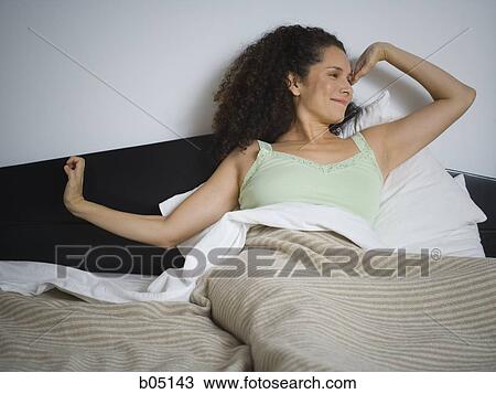 Woman in bed stretching and smiling View Large Photo Image Stock Image - Woman in bed stretching and smiling. Fotosearch
