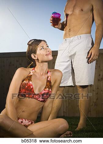 Woman in bikini looking up at man with cocktail View Large Photo Image Stock Photo - Woman in bikini looking up at man with cocktail. Fotosearch