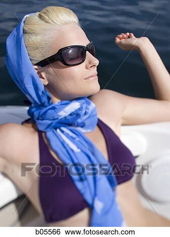 Stock Photograph - Woman in bikini on boat with headscarf and sunglasses. Fotosearch