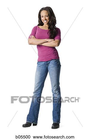Stock Image - Woman in blue jeans standing with arms crossed. Fotosearch