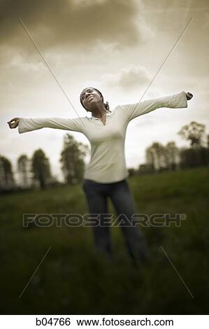Woman in grass field with arms up sepia View Large Photo Image Stock Photograph - Woman in grass field with arms up sepia. Fotosearch