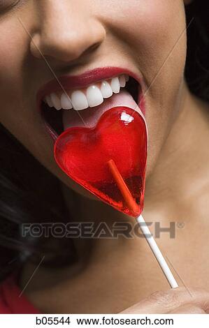 Woman licking heart shaped lollipop closeup View Large Photo Image Picture - Woman licking heart shaped lollipop closeup. Fotosearch