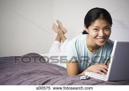 Stock Photography - Woman on bed with laptop. Fotosearch