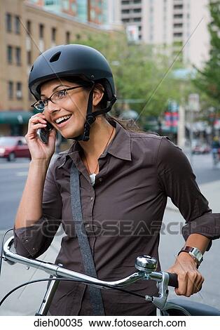 Stock Photography - Woman on bicycle talking on cell phone. Fotosearch