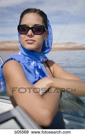 Stock Photo - Woman on boat with headscarf and sunglasses. Fotosearch