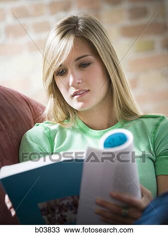 Stock Image - Woman on sofa reading. Fotosearch