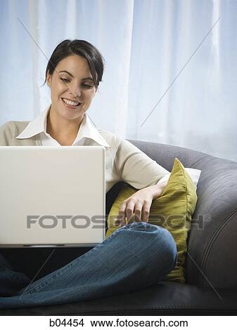 Picture - Woman on sofa with laptop. Fotosearch
