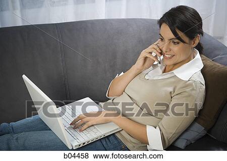 Stock Photo - Woman on sofa with laptop. Fotosearch