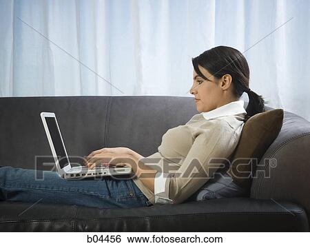 Stock Photograph - Woman on sofa with laptop. Fotosearch
