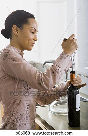 Woman opening a bottle of wine View Large Photo Image Stock Photo - Woman opening a bottle of wine. Fotosearch