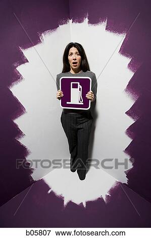 Woman painted into a corner and holding a gas sign View Large Photo Image Stock Photo - Woman painted into a corner and holding a gas sign. Fotosearch