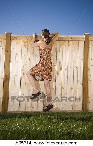 Woman peeping over wooden fence View Large Photo Image Picture - Woman peeping over wooden fence. Fotosearch