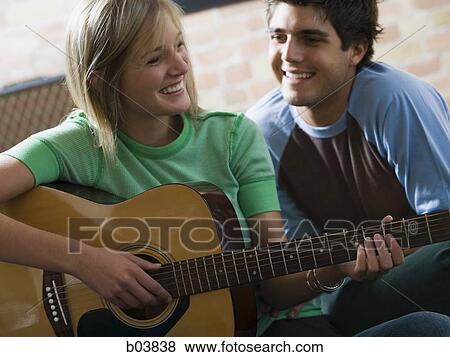 Woman playing guitar with man watching View Large Photo Image Stock Photo - Woman playing guitar with man watching. Fotosearch