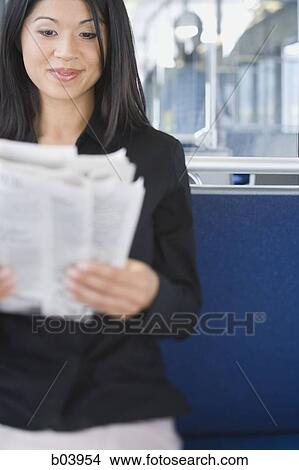 Picture - Woman reading newspaper on bus or subway. Fotosearch