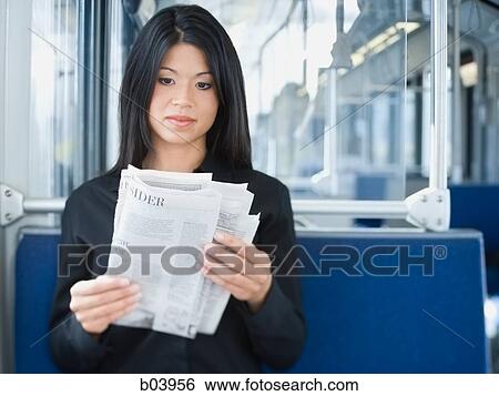 Stock Photograph - Woman reading newspaper on bus or subway. Fotosearch