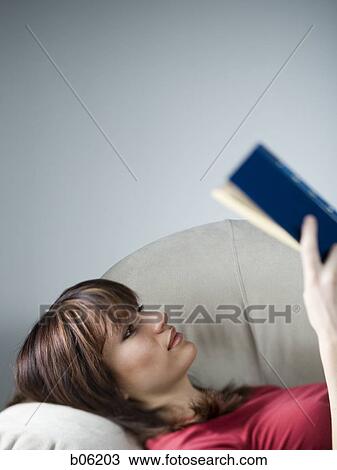 Stock Image - Woman reading on the couch. Fotosearch