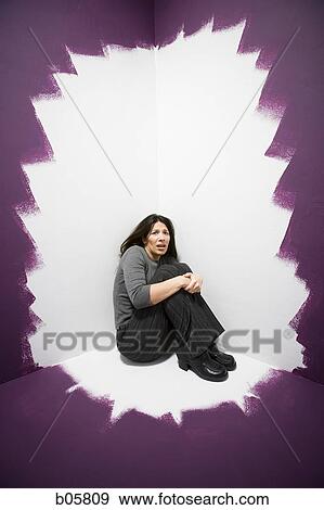 Woman sitting in a corner looking scared View Large Photo Image Stock Photo - Woman sitting in a corner looking scared. Fotosearch