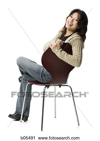 Stock Image - Woman sitting on chair smiling. Fotosearch