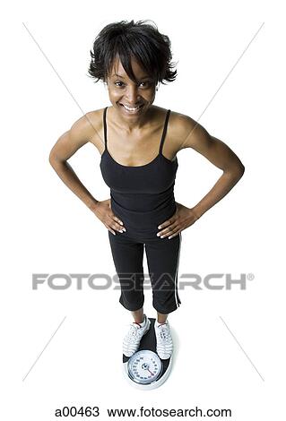 Stock Image - Woman standing on a weigh scale. Fotosearch