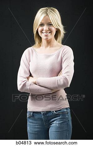 Stock Image - Woman standing with arms crossed smiling. Fotosearch