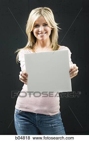 Stock Photo - Woman standing with blank sign smiling. Fotosearch