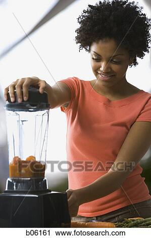 Stock Image - Woman using a blender. Fotosearch