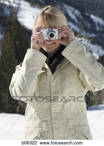 Stock Image - Woman using a camera outside. Fotosearch
