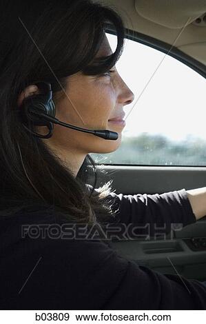 Woman wearing earphone driving car View Large Photo Image Stock Photo - Woman wearing earphone driving car. Fotosearch