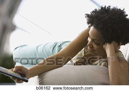 Stock Image - Woman with a remote control. Fotosearch