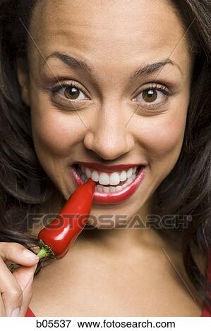 Stock Photo - Woman with red lipstick eating red pepper. Fotosearch