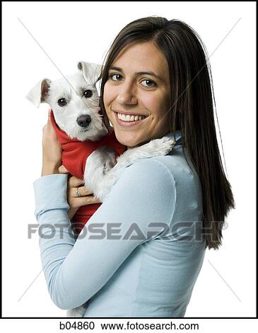 Stock Image - Woman with white dog in hooded sweatshirt. Fotosearch