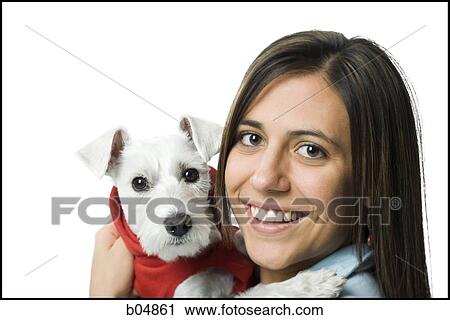 Stock Image - Woman with white dog in hooded sweatshirt. Fotosearch