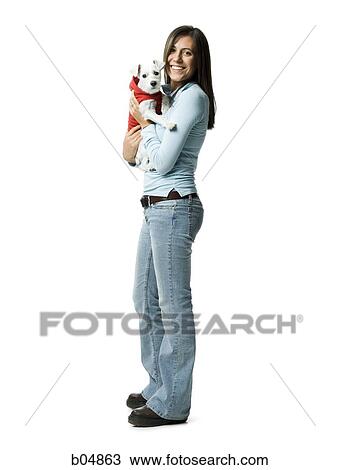 Stock Image - Woman with white dog in hooded sweatshirt. Fotosearch