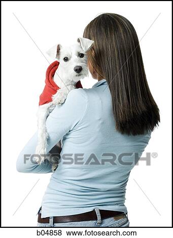 Stock Photo - Woman with white dog in hooded sweatshirt. Fotosearch