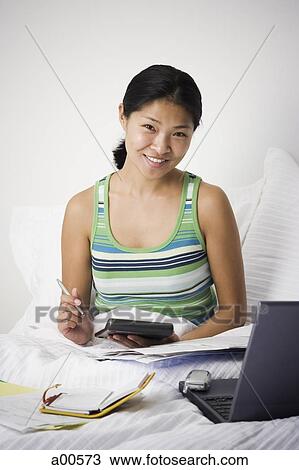 Stock Image - Woman working from bed. Fotosearch