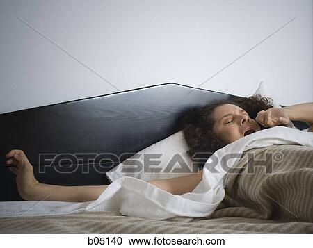 Stock Image - Woman yawning in bed. Fotosearch