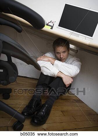 Young Businessman hiding under desk with arms crossed View Large Photo Image Stock Photography - Young Businessman hiding under desk with arms crossed. Fotosearch