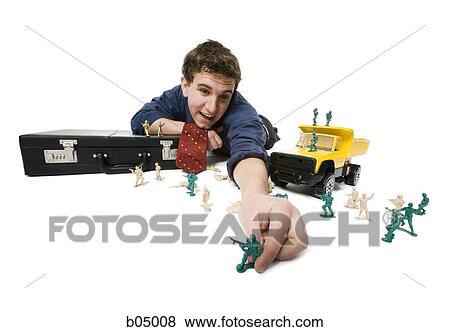 Young businessman playing with plastic army men and truck View Large Photo Image Stock Photo - Young businessman playing with plastic army men and truck. Fotosearch
