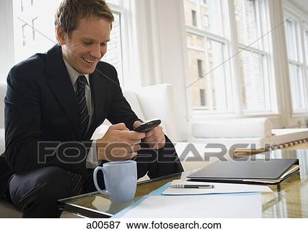 Young businessman sitting on sofa with blackberry smiling View Large Photo Image Stock Photo - Young businessman sitting on sofa with blackberry smiling. Fotosearch